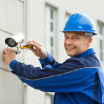 mature male technician installing camera on wall with screwdriver